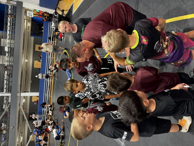 Coach giving instruction to young wrestlers